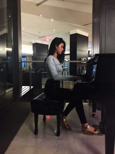 Aili playing a piano from a side angle